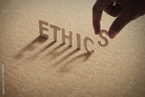 ETHICS wood word on compressed board with human's finger at S letter photo