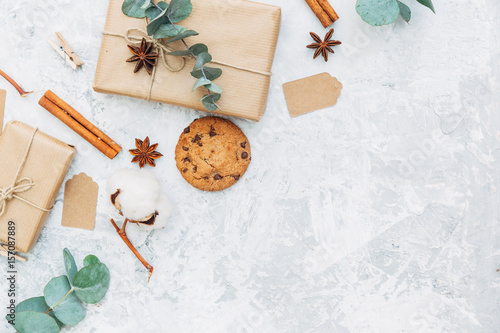 Gift or present box wrapped in kraft paper and green leaves on gray table from above. Flat lay styling. Copy space for text.