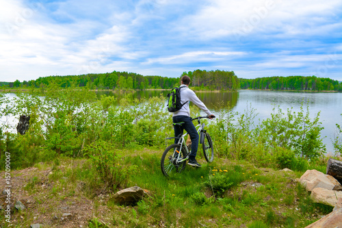 Biker with a mountain bike on the shore of a beautiful lake covered with greenery