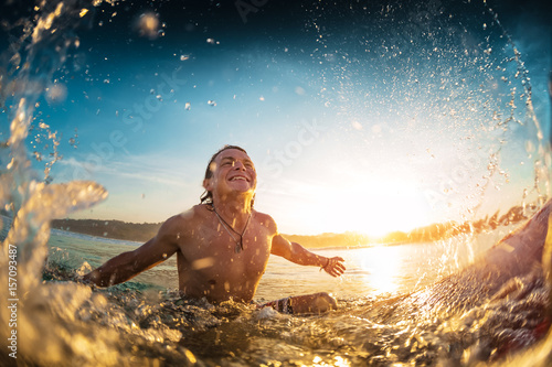 Happy surfer sits on board in the ocean