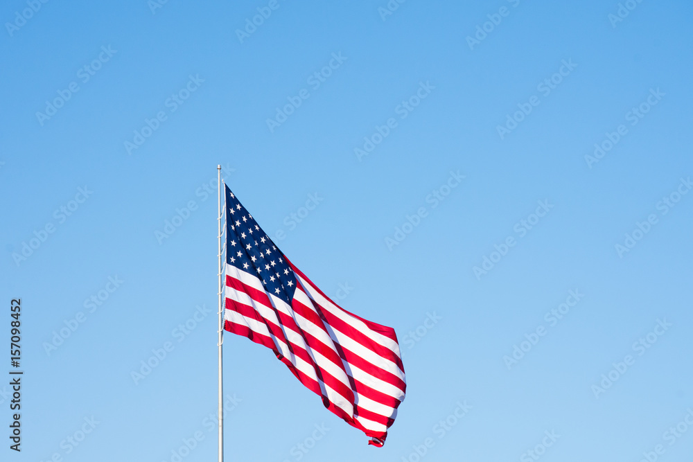 American Flag Against Cloudless Sky Unfurled in the Wind. Image has copy space. American Flag Against Cloudless Sky Unfurled in the Wind. Image has copy space.