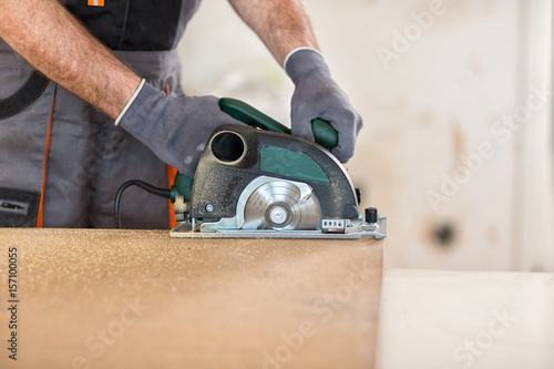 Carpenter cuts plywood with circular saw