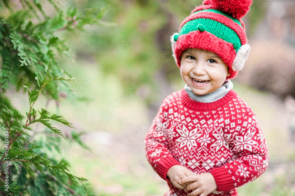 Little boy in sweater and hat waiting for a Christmas in the wood Little boy in sweater and hat waiting for a Christmas in the wood