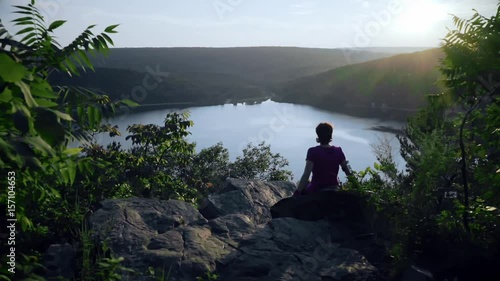 Woman seats on the mountain rocks and admiring a buatiful view