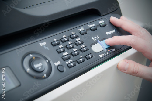 Finger on start button of laser printer