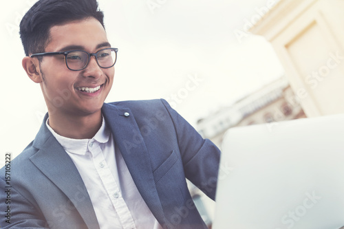 Smiling Asian businessman looking at laptop