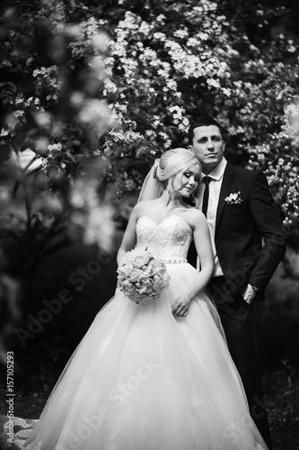 Beautiful couple walking in the park in their wedding day. Sunny weather. 