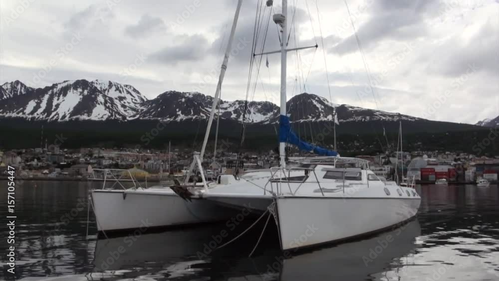 Wharf of yacht on background of clouds in sky and mountains on Falkland Islands. Beautiful landscape of wild nature. Quiet and calm ecotourism. Panorama of way to cold Antarctica.