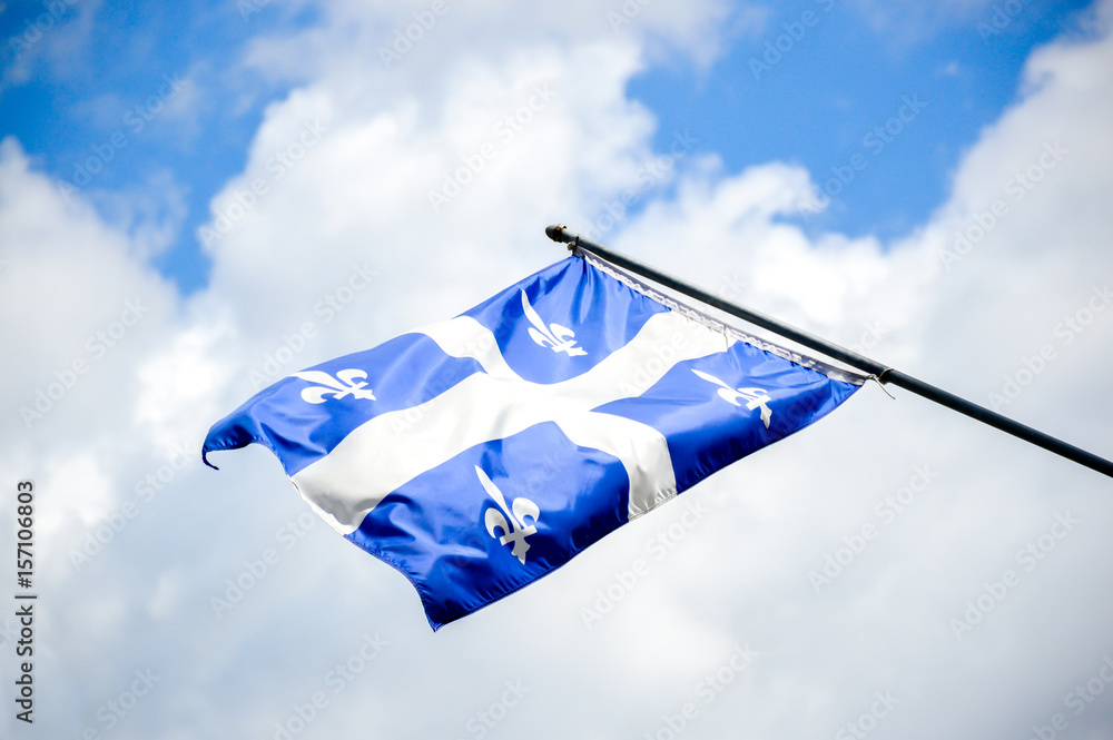 Naklejka premium Powiewająca flaga Quebecu na tle błękitnego nieba