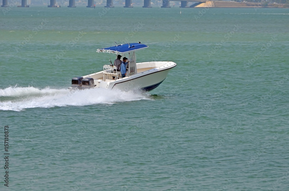 Fototapeta premium Small fishing boat p;owe red by two outboard engines speeding across the florida intra-coastal waterway off Miami Beach,
