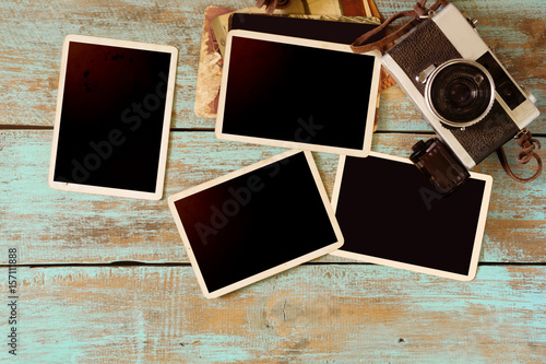 Retro camera and empty old instant paper photo album on wood table - blank photo frame vintage style