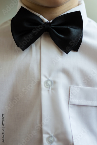 A boy in a business suit. The groom in a white shirt with a black butterfly. A small businessman. Children's holiday. Close-up