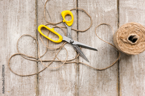 Scissors and rope on wooden background. Top view on workplace with diy tools. Decoration equipment, florist, decorator, handmade concept.