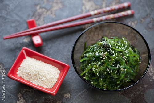 Bowl with seaweed salad and sesame seeds on a brown stone background, horizontal shot