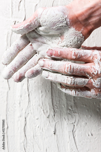 Worker hands in white stucco background, flat lay. Repair, construction work, building, plastering concept