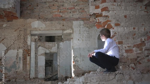 An orphan boy, a schoolboy sad in a ruined building after the war, lost, fear, loneliness