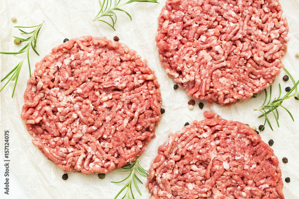 Raw hamburgers without fat from organic beef on a white wooden background with spices. Nourishing food. Top view. Raw hamburgers without fat from organic beef on a white wooden background with spices. Nourishing food. Top view.