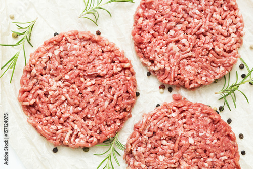 Raw hamburgers without fat from organic beef on a white wooden background with spices. Nourishing food. Top view.