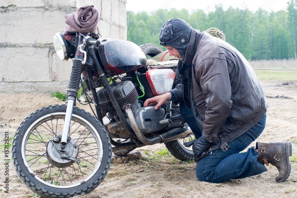 Fototapeta premium A post apocalyptic man on motorcycle near the destroyed building