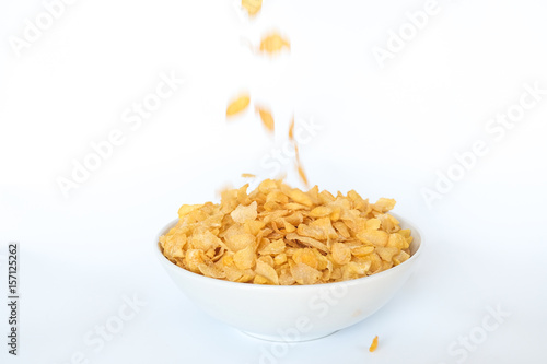 Corn flakes falling in bowl isolated on white background