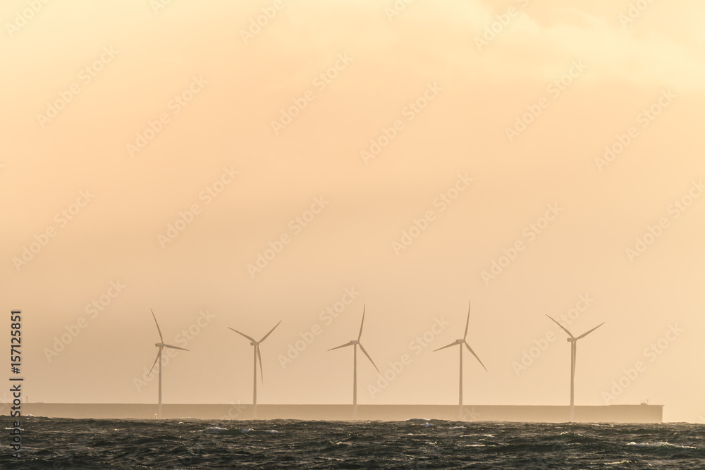 silhouetted wind farm at sea