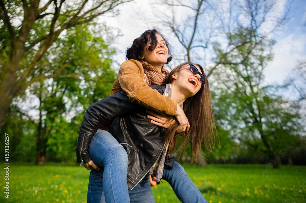 Fototapeta premium Two cute young women cheerfully spend time in the spring park