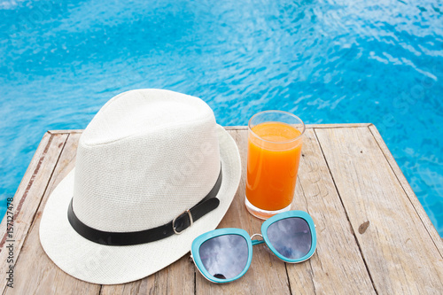 Summertime orange juice hat and sunglasses relax near swimming pool