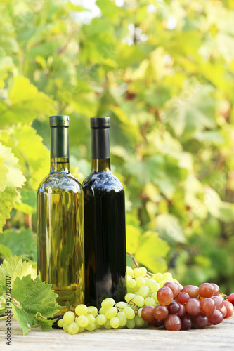 Wine in bottle with bunch of grape on wooden table