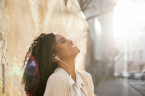 Beautiful black woman posing for ca,era with her head raised to the sky. Woman has headphones. photo