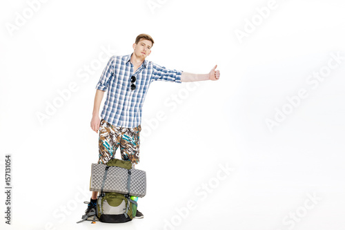 Fotografi Travel man hitchhiking. young male hitchhiker on white background