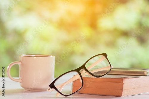 Morning coffee with glasses and book on white table