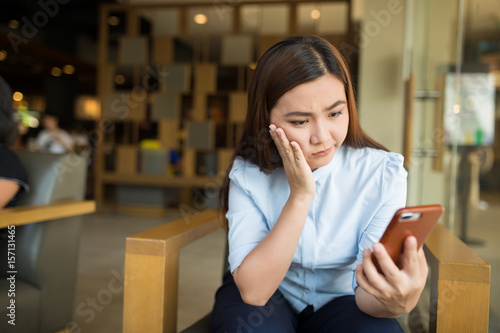 Woman using smartphone in cafe and she feel worried