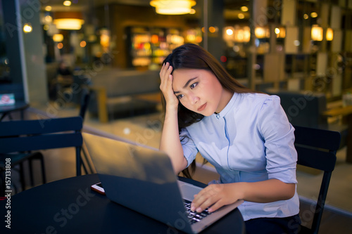 Woman using laptop in night time at cafe she feel worried