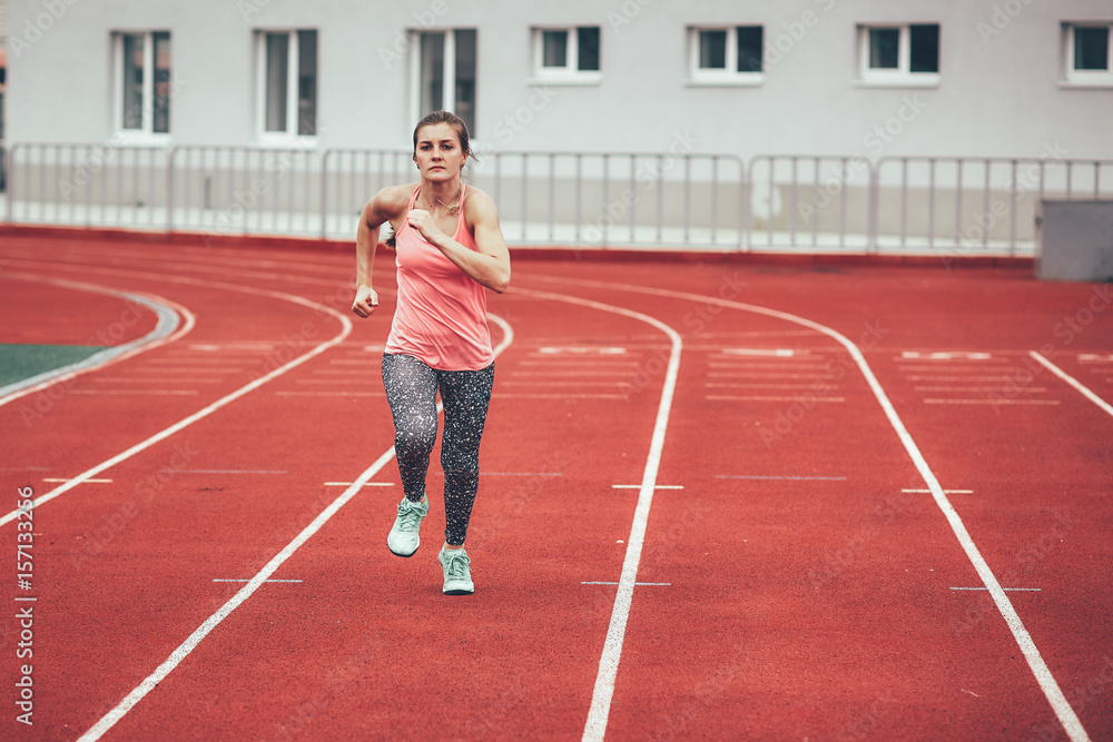 Track runner athlete woman warming up before running at a stadium