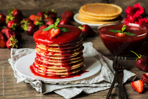 American pancakes and strawberry sauce on a wooden background. Shallow depth of field.