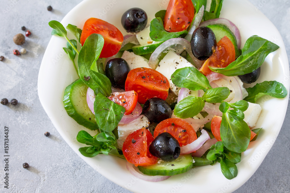 Greek salad with arugula, tomatoes, feta cheese, onions, cucumber and olives, seasoned with oil. Vitamin snack on the festive table close up. Greek salad with arugula, tomatoes, feta cheese, onions, cucumber and olives, seasoned with oil. Vitamin snack on the festive table close up.