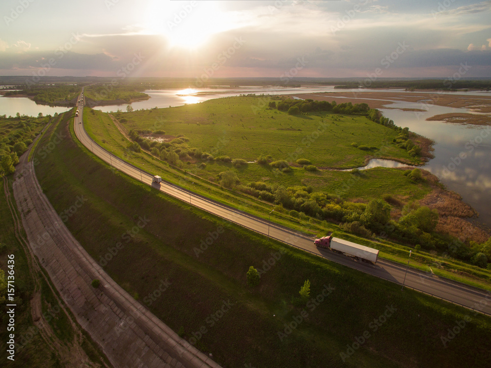 beautiful landscape with a ride on the highway the trucks and a few cars at sunset. aerial view