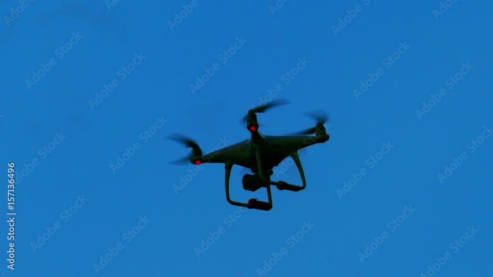 Silhouetted black drone flying in deep blue sky background.
Silhouetted black drone flying in deep blue sky background.