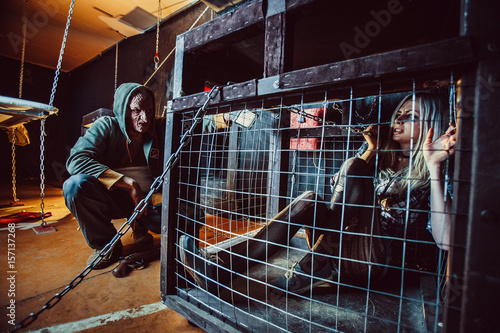 Bloody maniac and his female victim in the cage.