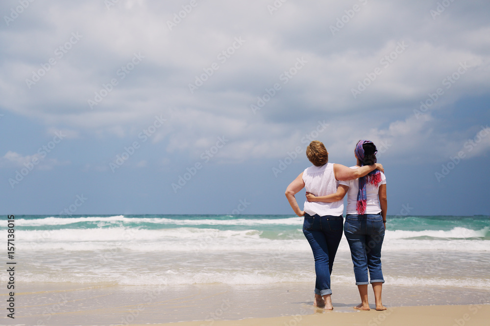 Outdoor portrait of two women standing on the beach Outdoor portrait of two women standing on the beach