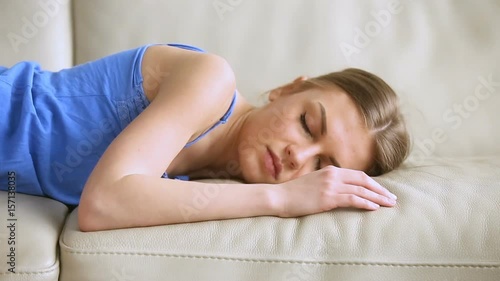 Young sleepy woman falling down on sofa at home with eyes closed, lying motionless fainted, feeling exhausted, falls asleep, lose consciousness, conk zonk out, dangerous weight-loss diet effect