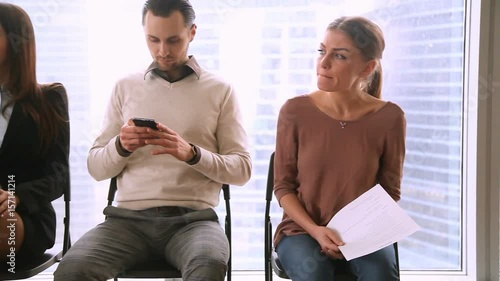 Business people group sitting in row on chairs, three job applicants await for their turn in queue, waiting for job interview concept, man and two women preparing for audition, feeling stressed bored photo