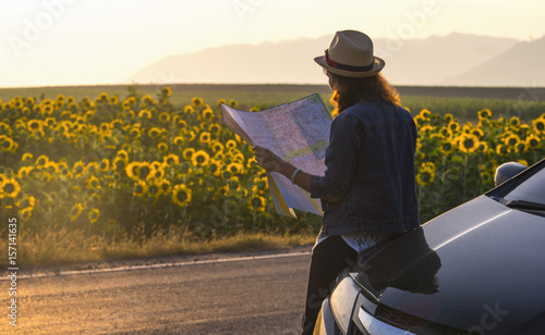 Cheerful woman wanderer with trendy look searching direction on location map while traveling abroad in summer, happy female tourist searching road to hotel on atlas in a foreign city during vacation photo