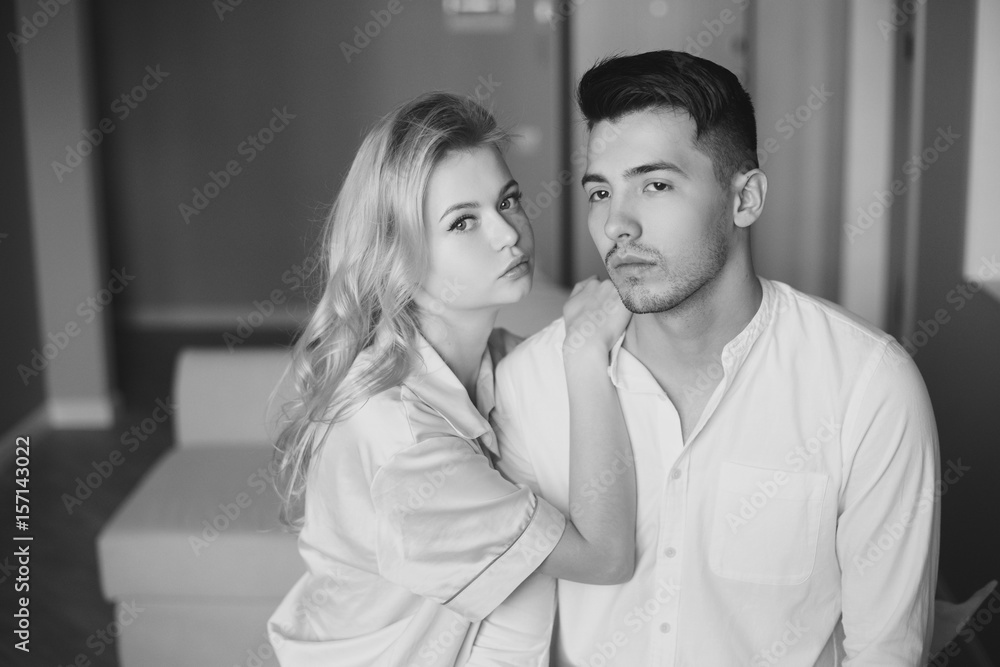 Young romantic couple at home. Caucasian blonde woman and brunette man. Lovers hugging in living room. Young romantic couple at home. Caucasian blonde woman and brunette man. Lovers hugging in living room.