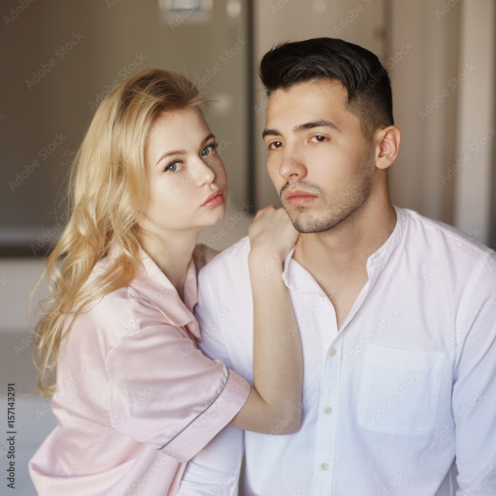 Young romantic couple at home. Caucasian blonde woman and brunette man. Lovers hugging in living room. Young romantic couple at home. Caucasian blonde woman and brunette man. Lovers hugging in living room.