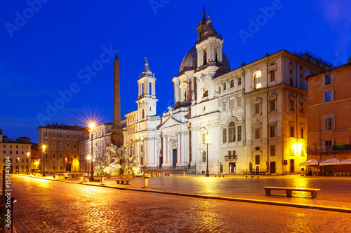 Fountain of the Four Rivers with an Egyptian obelisk and Sant Agnese Church on the famous Piazza Navona Square at night, Rome, Italy.