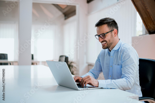 Portrait of young man sitting at his desk in the office