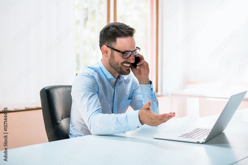 Young man using laptop and talking on the phone Young man using laptop and talking on the phone
