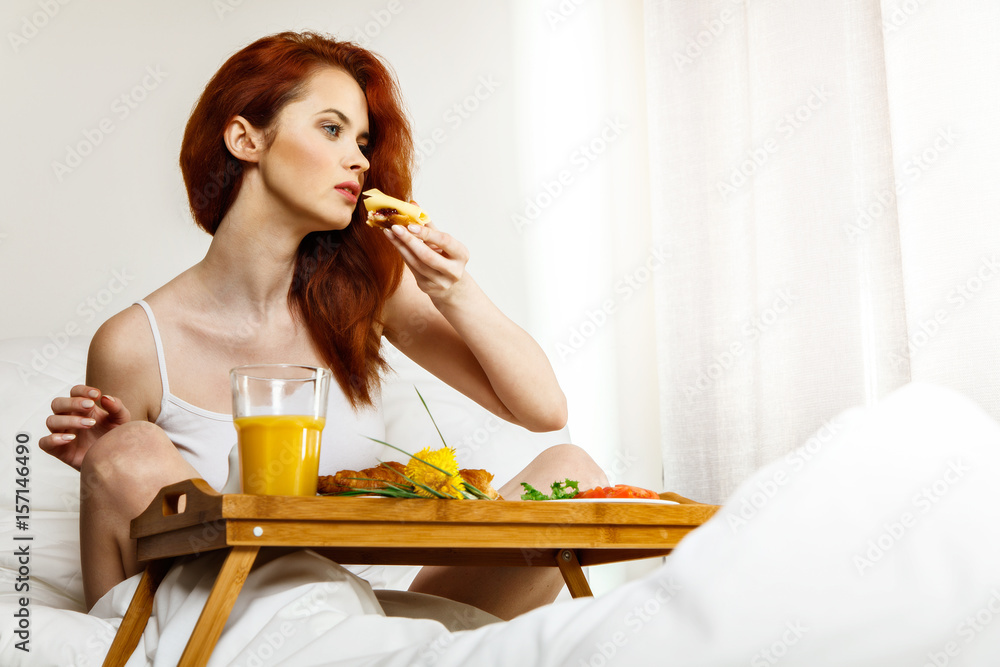 Young woman eats breakfast in bed in the morning Young woman eats breakfast in bed in the morning