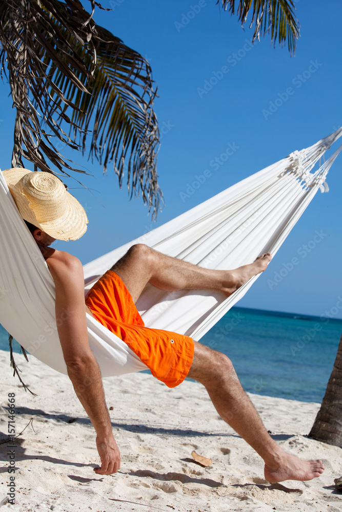 homme couché dans un hamac sur la plage avec un chapeau de paille Stock  Photo | Adobe Stock
